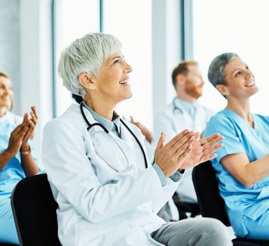 Portrait of a senior doctor applauding on a seminar in a board room or during an educational class at convention center