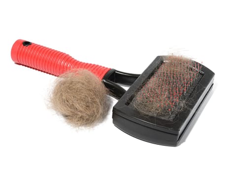 Plastic brush and combing out wool in animals and a tuft of gray cat hair on a white background