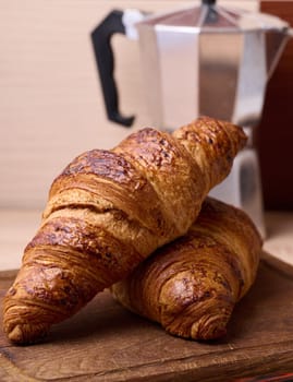 Baked crispy croissant on a wooden board, breakfast