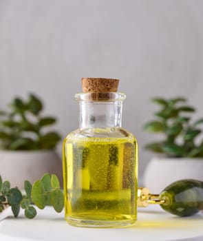 Transparent glass bottle with yellow oil and eucalyptus branch, cosmetic product