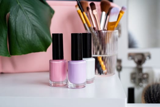 closeup of elegant cosmetic products standing on feminine dressing table, mockup design of nail polish bottle