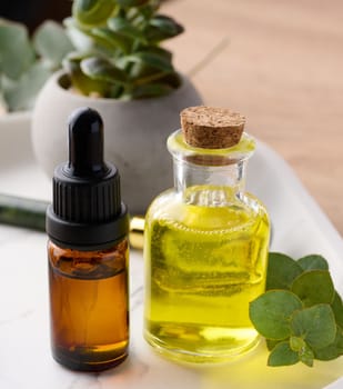 Transparent glass bottle with yellow oil and a brown bottle with a pipette , eucalyptus branch, cosmetic product