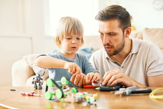 Portrait of a father and son, father teaching son to use tools and craftmenship with creative toy at home
