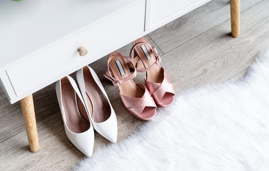 Stylish light room interior with elegant vanity table and plants, beauty and fashion. closeup of elegant high heel shoes standing under dressing table, mockup