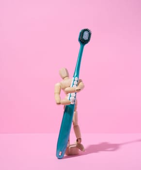 Wooden puppet toy holding a toothbrush on a pink background