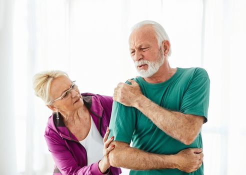 Senior couple exercising at home, suffering a shoulder injury pain health care