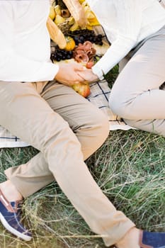 Man and woman are sitting on a blanket holding hands. Cropped. High quality photo