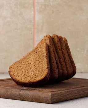 Triangular rye piece of bread on a wooden cutting board