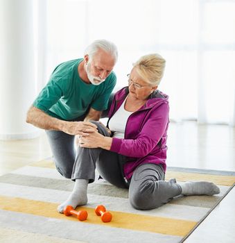 Senior couple exercising at home, suffering a knee injury pain health care
