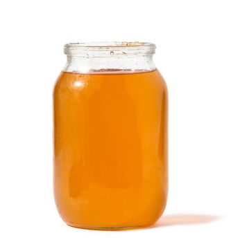 Transparent glass jar with bee honey on a white isolated background