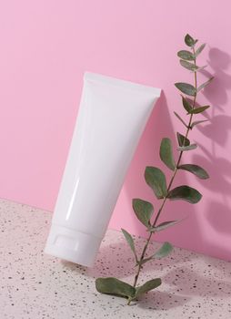 White plastic tube for liquid cosmetics on a pink background, packaging