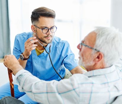 Doctor or nurse caregiver showing a tablet screen to senior man at home or nursing home