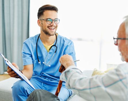 Doctor or nurse caregiver showing a tablet screen to senior man at home or nursing home