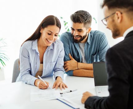 Real estate agent with couple closing a deal and signing a contract