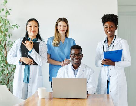 portrait of a doctors and nurses with laptop sitting by desk on their office