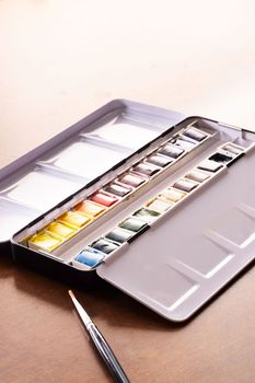 Watercolor tin with pans of colorful paint and brush