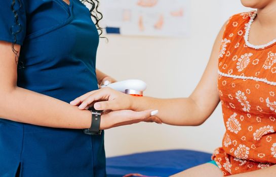 Close up of physiotherapist using laser therapy on patient arm, Modern laser physiotherapy on patient. Laser therapy used on the arm to treat pain