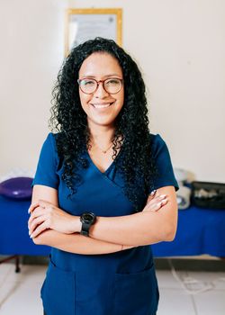 Portrait of smiling woman physiotherapist. Crossed arms african american physical therapist woman. Smiling woman chiropractor in uniform with arms crossed