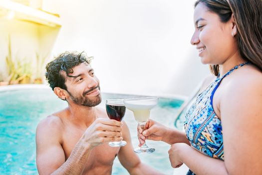 Smiling couple toasting in the pool. Man and woman on vacation toasting in the pool. Concept of couple on vacation toasting in the pool