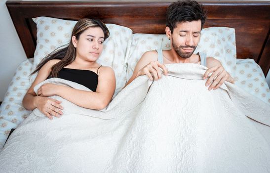 Worried husband with erectile dysfunction in bed. Disappointed man in bed with erectile dysfunction. Concept of couple sexual problems. Couple in bed upset about sexual dysfunction