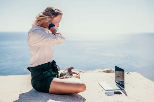 Happy girl doing yoga with laptop working at the beach. beautiful and calm business woman sitting with a laptop in a summer cafe in the lotus position meditating and relaxing. freelance girl remote work beach paradise