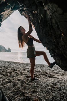 A girl climbs a rock. The athlete trains in nature. Woman overcomes difficult climbing route. Extreme hobby. Tourist woman rock climber hiking on mountains rocks over beautiful sea coast