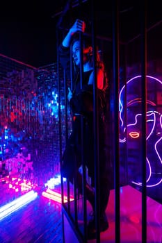 Caucasian woman in neon studio behind steel bars