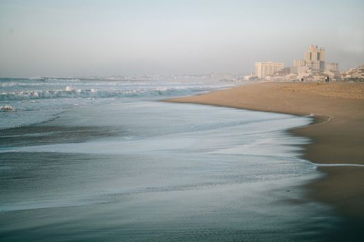 Sea saves reaching beach at praia de silvalde in Espinho , portugal , at sunset.