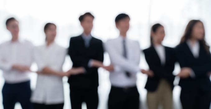 Blurry image of businesspeople holding their hand in line as to show concept of unity teamwork and harmony in office workplace. Office worker standing in line and join hands as collective from.
