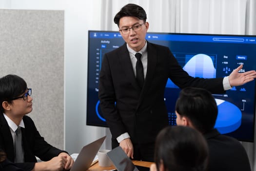 Confidence and asian businessman give presentation on financial analyzed by business intelligence in dashboard report to other people in board room meeting to promote harmony in workplace.