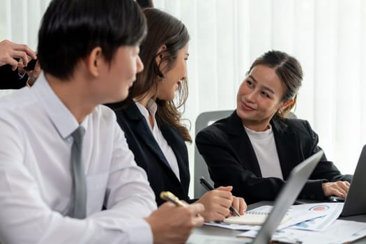 Harmony in office concept as business people analyzing dashboard paper together in workplace. Young colleagues give ideas at manager desk for discussion or strategy planning about project.