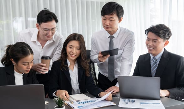 Harmony in office concept as business people analyzing dashboard paper together in workplace. Young colleagues give ideas at manager desk for discussion or strategy planning about project.