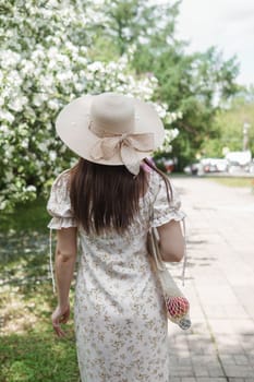 An attractive long-haired woman walks in the spring in the park of blooming apple trees. Spring portrait of a woman