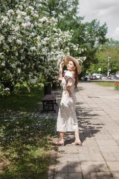 An attractive long-haired woman walks in the spring in the park of blooming apple trees. Spring portrait of a woman