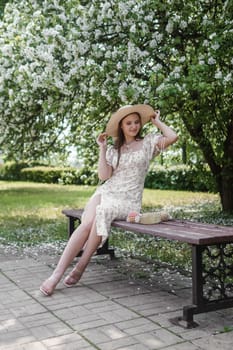 An attractive long-haired woman walks in the spring in the park of blooming apple trees. Spring portrait of a woman