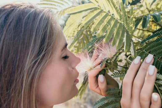 Beauty portrait of young woman closeup. Young girl smelling Chinese acacia pink blossoming flowers. Portrait of young woman in blooming spring, summer garden. Romantic vibe. Female and nature.