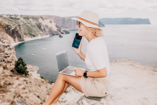 Digital nomad, Business woman working on laptop by the sea. Pretty lady typing on computer by the sea at sunset, makes a business transaction online from a distance. Freelance remote work on vacation