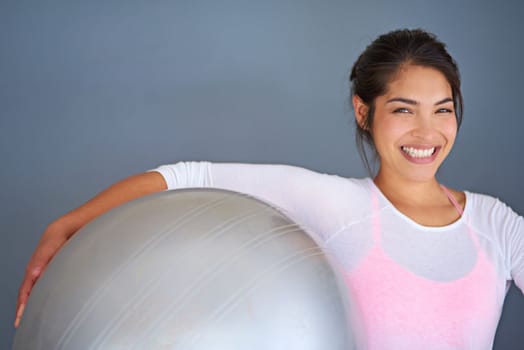 Youre one workout away from a good mood. a sporty young woman holding a pilates ball against a grey background