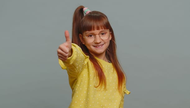 Like. Happy young preteen child girl kid looking approvingly at camera showing thumbs up, like sign positive something good, positive feedback. Toddler children isolated on studio gray background