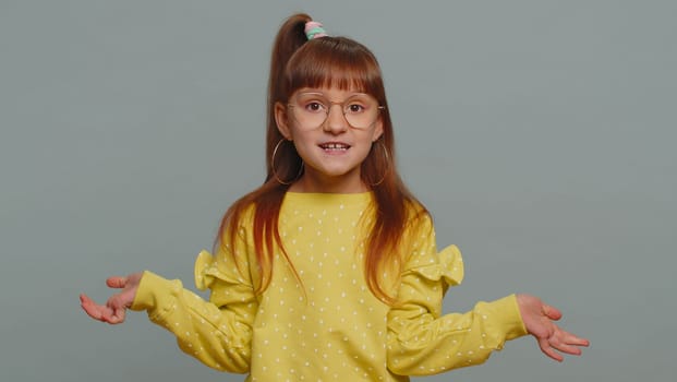 I dont know what to say. Confused young toddler school girl feeling embarrassed about ambiguous question having doubts no idea, being clueless and uncertain. Teen female child kid on gray background