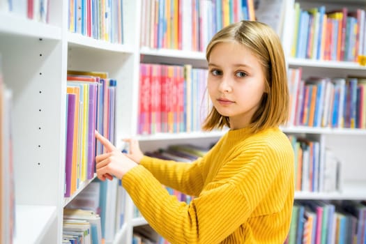 Schoolgirl choosing book in school library. Smart girl selecting literature for reading. Books on shelves in bookstore. Learning from books. School education. Benefits of everyday reading