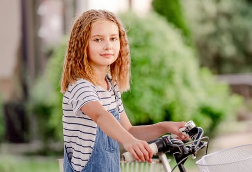 Cute litte girl sitting parking a kick scooter on a bicycle parking