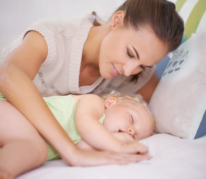 Shes always close to her baby. A young mother lying next to her sleeping baby on the bed