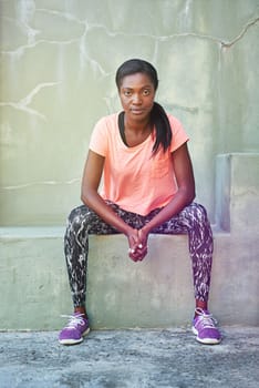 Ready for a workout. Portrait of an attractive and sporty young woman sitting outdoors