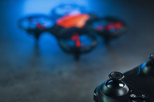 A reconnaissance quadcopter drone with an orange body and blue LED backlight on a dark background