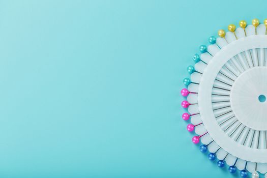 Sewing mother-of-pearl pins in a round white package on a blue background with free space