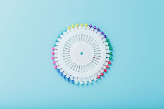 Sewing mother-of-pearl pins in a round white package on a blue background with free space