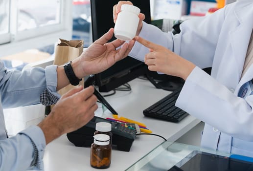 Closeup professional pharmacist advise or explain property of qualified medical product to customer in pharmacy, druggist answer to client healthcare inquiry, medical service and consultation concept.