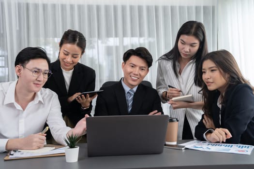 Harmony in office concept as business people analyzing dashboard paper together in workplace. Young colleagues give ideas at manager desk for discussion or strategy planning about project.