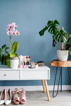 Stylish light room interior with elegant vanity table and plants, beauty and fashion